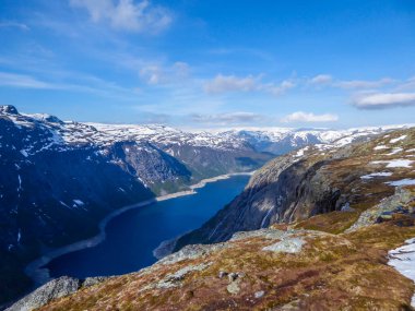 A panoramic view from above on a fjord-like Ringedalsvatnet lake, Norway . Snow-capped mountains. Spring slowly coming to the higher parts of the mountains. Water of the lake has a navy blue shade.