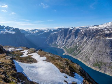 A panoramic view from above on a fjord-like Ringedalsvatnet lake, Norway . Snow-capped mountains. Spring slowly coming to the higher parts of the mountains. Water of the lake has a navy blue shade.