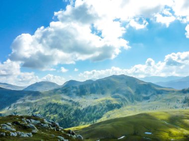 Hiking trails in the high mountain. Lush green grass covers the slopes. Endless chains of mountains visible. Great overcast, but the sun still prevails over them. Spring in the mountains.