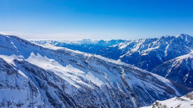 A beautiful and serene landscape of mountains covered with snow. Thick snow covers the slopes. Clear weather. Sharp slopes of the mountains covered with snow, with partially visible rocks.