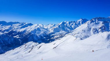 A beautiful and serene landscape of mountains covered with snow. Thick snow covers the slopes. Clear weather. Sharp slopes of the mountains covered with snow, with partially visible rocks.