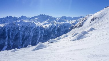 A beautiful and serene landscape of mountains covered with snow. Thick snow covers the slopes. Clear weather. Sharp slopes of the mountains covered with snow, with partially visible rocks.