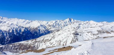 A beautiful and serene landscape of mountains covered with snow. Thick snow covers the slopes. Clear weather. Sharp slopes of the mountains covered with snow, with partially visible rocks.