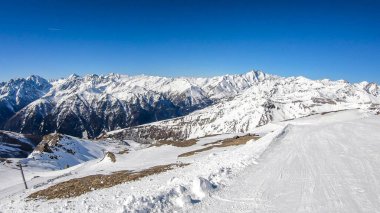 A beautiful and serene landscape of mountains covered with snow. Thick snow covers the slopes. Clear weather. Sharp slopes of the mountains covered with snow, with partially visible rocks.