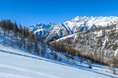 A beautiful and serene landscape of mountains covered with snow. Thick snow covers the slopes. Clear weather. Sharp slopes of the mountains covered with snow, with partially visible rocks.