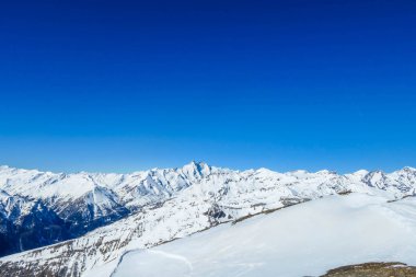 A beautiful and serene landscape of mountains covered with snow. Thick snow covers the slopes. Clear weather. Sharp slopes of the mountains covered with snow, with partially visible rocks.