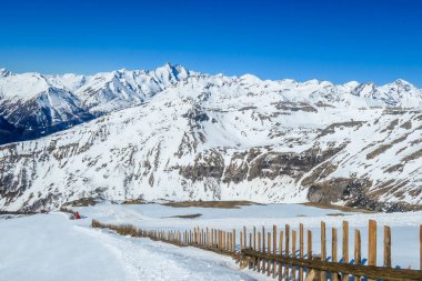 A beautiful and serene landscape of mountains covered with snow. Thick snow covers the slopes. Clear weather. Sharp slopes of the mountains covered with snow, protection fence on the side.