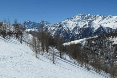 A beautiful and serene landscape of mountains covered with snow. Thick snow covers the slopes. Clear weather. Sharp slopes of the mountains covered with snow, with partially visible rocks.