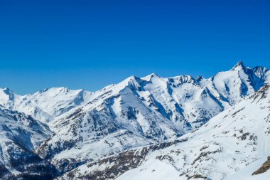 A beautiful and serene landscape of mountains covered with snow. Thick snow covers the slopes. Clear weather. Sharp slopes of the mountains covered with snow, with partially visible rocks.