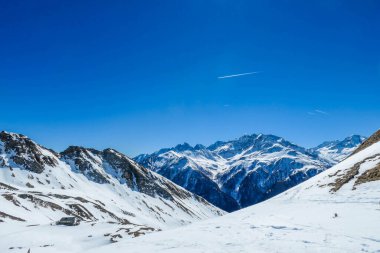 A beautiful and serene landscape of mountains covered with snow. Thick snow covers the slopes. Clear weather. Sharp slopes of the mountains covered with snow, with partially visible rocks.