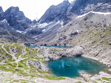 Valley with a small lake in the middle, located between sharp and stony mountain range of Lienz Dolomites, Austria. The slopes are barren, with little grass on it. Dangerous mountain climbing.