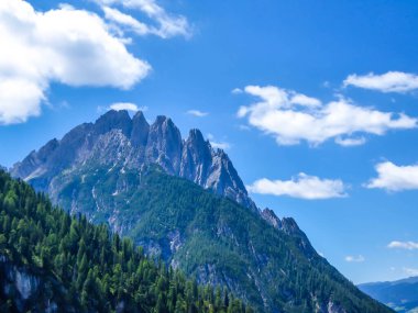 Distance view on tall and sharp mountain peaks of Lienz Dolomites, Austria. The peaks are barren, with little bushes growing on the slopes on it. Dangerous mountain climbing. Clear and bright day.