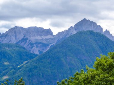 A distanced view on sharp and stony mountain range of Lienz Dolomites, Austria. The slopes are barren, with little grass on it. Dangerous mountain climbing. Clear and beautiful day. Natural beauty