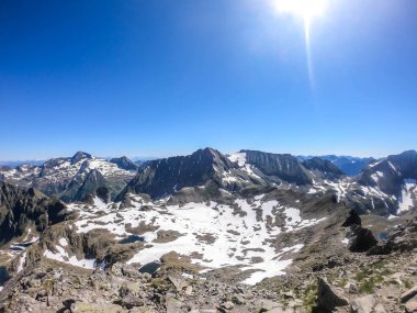 A panoramic view on Schladming Alps, partially still covered with snow. Spring slowly reaching the tallest parts of the mountains. Sharp peaks, slopes partially overgrown with lush green plants.