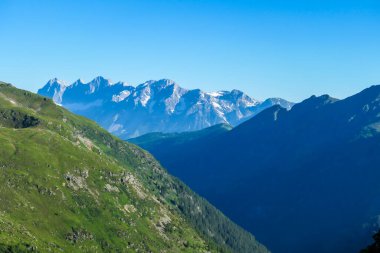 Massive mountain range of Schladming Alps, Austria. The slopes of Alps are steep, partially overgrown with green bushes. Dangerous mountain climbing.Clear and beautiful day. Endless mountain ranges,