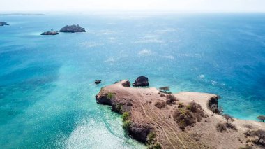 Beautiful headland formations on Lombok, Indonesia. Boats parked on the shores on the Pink Beach, Crystal clear water, shimmering with shades of blue. Drone areal capture. Hidden, unspoiled gem.