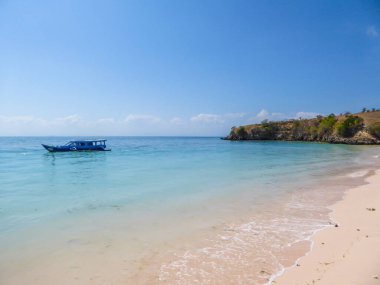 A peaceful Pink Beach in Lombok, Indonesia. Some boats are placed on the shore, others are drifting on a calm surface of the sea. Hidden gem of Indonesia, unspoiled place by humans. Relaxation