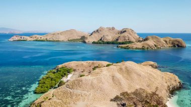 A drone shot of two bigger paradise islands in Komodo National Park, Flores, Indonesia. The islands have scarcely any trees and bushes. Dry land. Idyllic white sand beaches. Island hoping