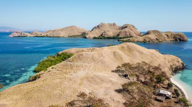 A drone shot of two bigger paradise islands in Komodo National Park, Flores, Indonesia. The islands have scarcely any trees and bushes. Dry land. Idyllic white sand beaches. Island hoping
