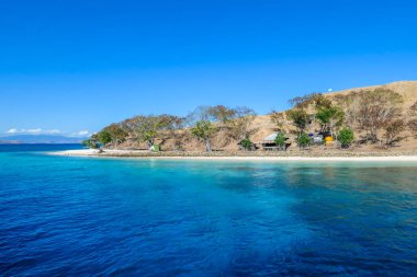 A panoramic view of idyllic white sand beach in Komodo National Park, Flores, Indonesia. Beach is gently washed by waves. Island has scarcely any plants on it. Idyllic location. Serenity and calmness