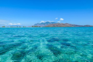Crossing the calm sea with an island view in the back in Flores, Indonesia. The sea has clear turquoise color, exposing the beautiful coral reef. Calmness and serenity. Discovering new places.