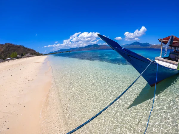 A view on a hull of a boat anchored to a beach on an island near Maumere, Indonesia. Boat is anchored with a blue rope. Clear, turquoise coloured water displaying coral reef. Fishing boat