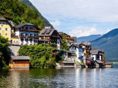 Small village located by the lake in Hallstatt, Austria. The houses have many different colors. Alpine village. Idyllic landscape. Coexistence of human and nature. High mountains rising from the lake