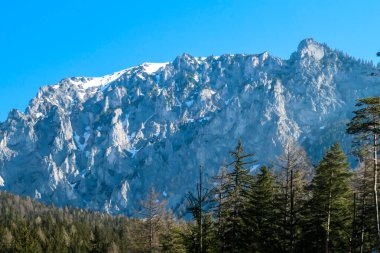 A peaceful view on an Alpine valley in Austria. The valley has a Green Lake in the middle. Early spring in the mountains. There is a high mountain range in the back, towering above the valley