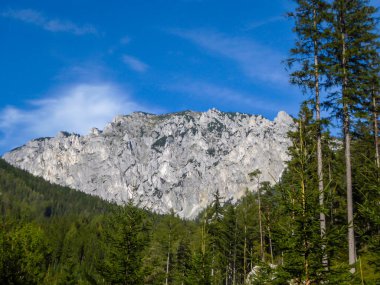 A peaceful view on an Alpine valley in Austria. The valley has a Green Lake in the middle. Early spring in the mountains. There is a high mountain range in the back, towering above the valley