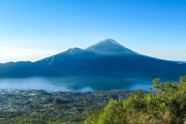 An idyllic view from the top of Mount Batur on Mount Agung and the Danau Batur lake. There is a pathway along Batur volcano's rim. Volcanic landscape of Bali, Indonesia. Island hiking.