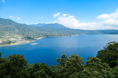 A panoramic view on The Twin Lake, Bali, Indonesia. The lake is surrounded by lush green plants. There are small hills all around the lake. Touristic attraction. Biggest lake on Bali