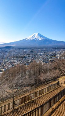 A distant view on Mt Fuji in Japan on a clear, wintery day. The top parts of the volcano are covered with a layer of snow. There is a pathway below. Holly mountain of Japan.