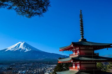 View on Chureito Pagoda and mountain of the mountains Mt Fuji, Japan, captured on a clear, sunny day in winter. Top of the volcano covered with snow. Trees aren't blossoming yet. Postcard from Japan.