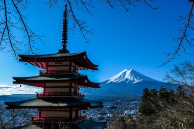 View on Chureito Pagoda and mountain of the mountains Mt Fuji, Japan, captured on a clear, sunny day in winter. Top of the volcano covered with snow. Trees aren't blossoming yet. Postcard from Japan.