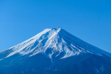 A distant, close up view on Mt Fuji in Japan on a clear, wintery day. Inaccessible slopes of the mountains are covered with a thick layer of snow. Holly mountain of Japan.