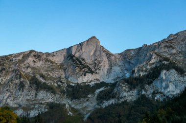 A vast view on an Alpine valley in the region of Hochschwab, Austria. High mountain ranges surrounding the road in the valley. Soft morning haze. Exploration and achievement