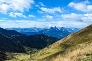 A drone shot of Alpine landscape of Austria. Sharp slopes of both side of the valley. Hard to reach mountain peaks. There are many mountain ranges in the back. Serenity and calmness