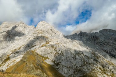 Golden colored mountains range at Austrian-Italian border. The autumn vibes in Alps, nature getting ready for hibernation. Sharp rocky Alpine peaks. Serenity and peace. Clouds breaching high mountains