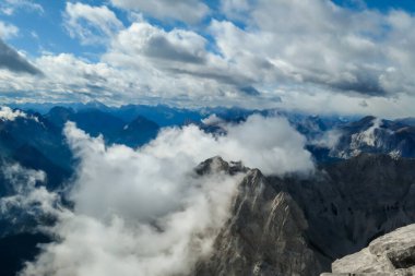 Sharp and rocky mountains range at Austrian-Italian border. There s a path mark on a stone. Serenity and peace. Clouds breaching high mountains. Lots of loose rocks, possibility of landslide
