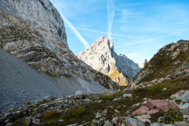 Sharp and rocky mountains range at Austrian-Italian border. There s a path mark on a stone. Serenity and peace. Lots of mountain ranges n the back. Lots of loose rocks, possibility of landslide