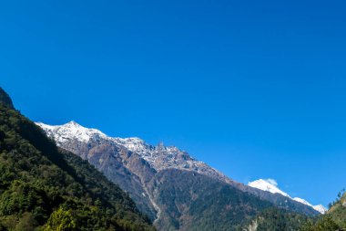 View on Himalayas, Annapurna Circuit Trek, Nepal. Early morning in the mountains. Lower parts of the mountains covered in shadow, high snow caped mountains peaks catching the first beams of sunlight