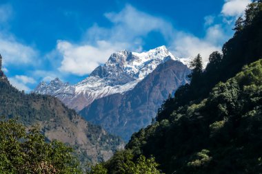 View on Himalayas, Annapurna Circuit Trek, Nepal. Early morning in the mountains. Lower parts of the mountains covered in shadow, high snow caped mountains peaks catching the first beams of sunlight
