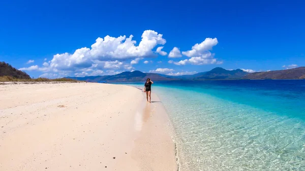 在印度尼西亚毛姆雷附近的一个小岛上 身穿黑色T恤衫的女孩走在白色沙滩上 快乐和粗心的时刻 波浪冲刷着海岸 显示珊瑚礁的蓝绿色海水 — 图库照片