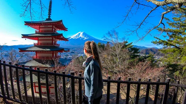 晴れた冬の晴れた日に撮影された 日本の富士山を望む美少女 火山の頂上は雪で覆われていた 女の子は 自然の美しさを考えて 彼女の時間を楽しんでいる — ストック写真