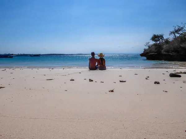 一对夫妇坐在印度尼西亚伦博克的平克海滩上 他们享受着天国的美景 水有许多深蓝色 海滩被小山环绕着 天堂海滩1 团结与幸福 — 图库照片