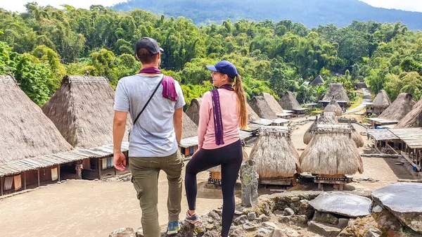 一对带着紫色围巾的夫妇欣赏印度尼西亚弗洛雷斯的Beno村 他身后有许多小房子 每栋房子都是由木头和稻草等天然部件组成的 历史和传统 — 图库照片