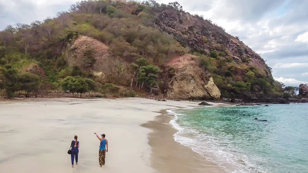 一对夫妇在田园诗般的科卡海滩上散步 印度尼西亚弗洛雷斯隐藏的宝石 情侣们正在享受他们浪漫的逃离 波浪轻柔地冲刷着海岸 后面有小山 幸福与爱情 — 图库照片