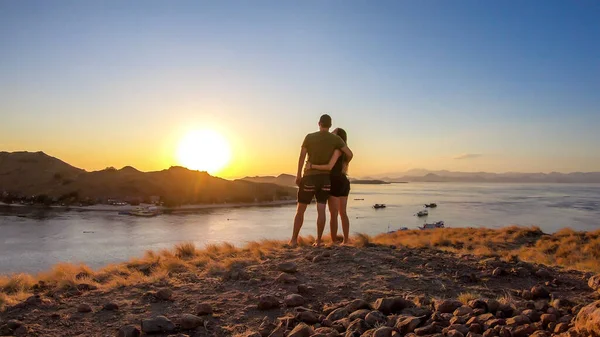 一对夫妇站在一个小岛上拥抱 在印尼弗洛雷斯科莫多国家公园的上空享受早晨的阳光 岛上和海上的黄金时刻 他们正在享受他们的时光 — 图库照片