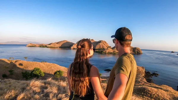 一对夫妇站在一个小岛上拥抱 在印尼弗洛雷斯科莫多国家公园的上空享受早晨的阳光 岛上和海上的黄金时刻 他们正在享受他们的时光 — 图库照片