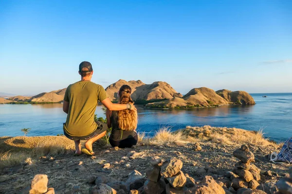 一对夫妇坐在一个小岛上 在印度尼西亚弗洛雷斯科莫多国家公园的上空享受晨阳 岛上和海上的黄金时刻 他们正在享受他们的时光 爱与幸福 — 图库照片